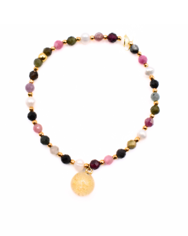 Bransoletka handmade z wielokolorowych kamieni i pereł, z zawieszką z żywicy w złotym odcieniu z dmuchawcem – widok z góry.