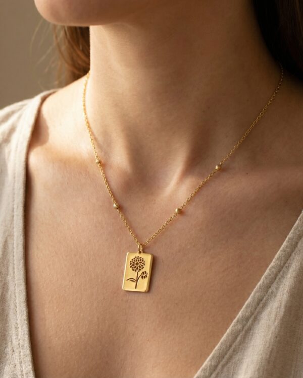 A close-up of a gold necklace featuring a floral design, worn by a woman.