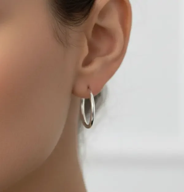 Earrings in the shape of thin hoops worn by a model.