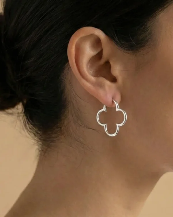 A model showcasing silver clover-shaped earrings.